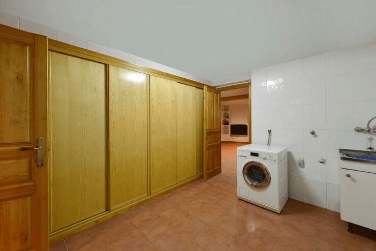 An in-unit laundry room with a washing machine and cabinets